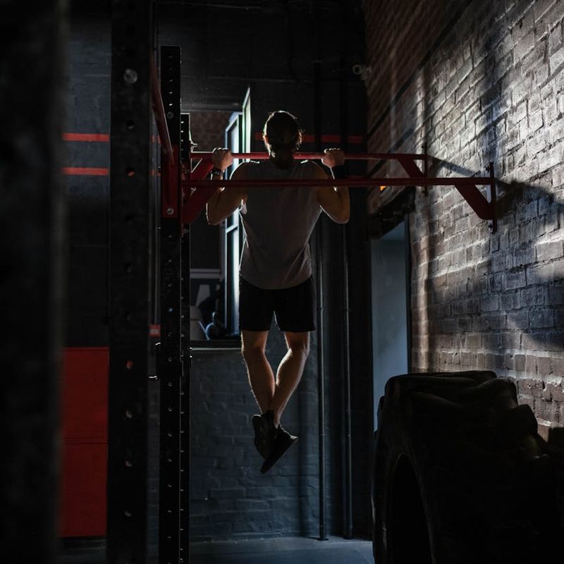 Close-up on athletic man's hands gripping a pull-up bar.